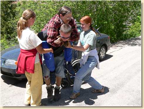 Lezli & Heidi help load Fred Adams onto son Daniel's back