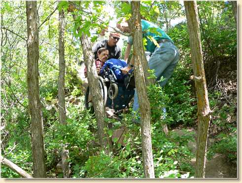 Daniel Adams and Tom Hunt help Fred Adams down steep trail