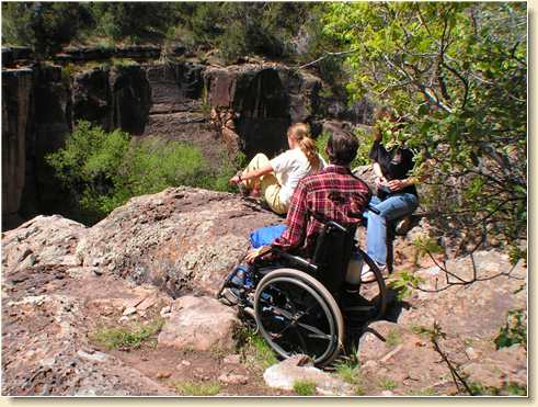 Fred Adams in wheelchair at top of rappelling cliffs