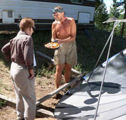 Jim Conrad showing solar cooker concoction to visitor