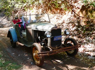 Ford Roadster with kids throwing up arms as if in a roller coaster.